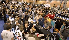 Collectors and enthusiasts browsing knife displays at a busy trade show, included to represent the Blade Vault community and highlight the marketplace’s focus on connecting knife collectors for buying, selling, and trading.